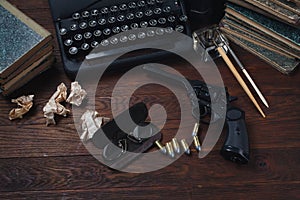 Writing a crime fiction book - old retro vintage typewriter and revolver gun with ammunitions, books, papers, old ink pen