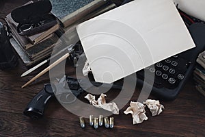 Writing a crime fiction story - old retro vintage typewriter and revolver gun with ammunitions, books, blank paper, old ink pen
