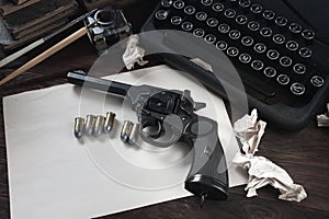 Writing a crime fiction story - old retro vintage typewriter and revolver gun with ammunitions, books, blank paper, old ink pen