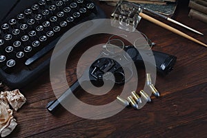 Writing a crime fiction story - old retro vintage typewriter and revolver gun with ammunitions, books, papers, old ink pen