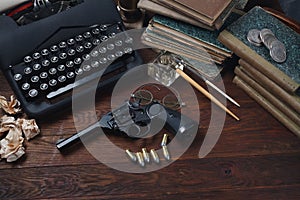 Writing a detective story - old retro vintage typewriter and revolver gun with ammunitions, books, papers, old ink pen