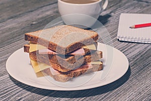 Writing essay business education food snack eating concept. Business breakfast. Tasty ham and cheese sandwich with cup of coffee,