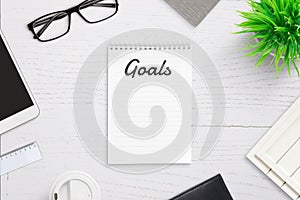 Writing goals on empty notepad page with goals title in header
