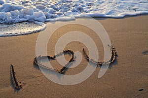 Writing and a heart on the sand with a wave