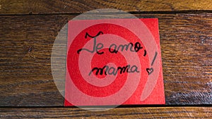 Writing I love you, mom in Spanish (te amo, mama) on memo post reminder. Text on sticky paper. Mother`s day concept