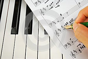 Writing on music score with pen on piano keyboard