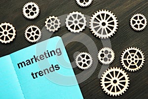 Writing note showing marketing trends. Small wooden gears, wooden background are on the photo
