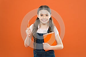 Writing notes. kid diary. school girl read book on orange background. happy little girl with notebook. poetry and novel