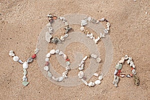 Writing with shells text Yoga on beach