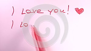 Writing text - I love you with heart. Red felt tip pen on pink background.