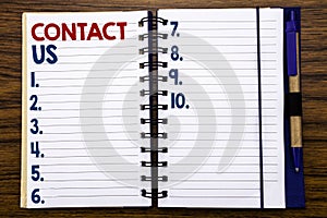 Writing text showing Contact Us. Business concept for Customer Support Written on notebook note paper, wooden background with pen