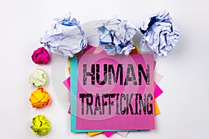 Writing text showing Human Trafficking written on sticky note in office with paper balls. Business concept for Slavery Crime