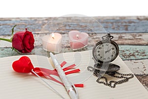 Writing time for love: red rose, journal, pen, and pocket watch