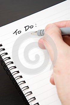 Writing TO DO in a blank spiral-bound notebook