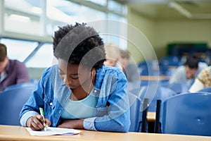 Writing, university and black woman student in classroom studying for test, exam or assignment. Education, college and