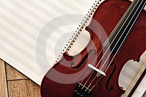 Writing Violin Music. Close up view of beautiful brown violin lying on sheets for music notes. Musical instruments.