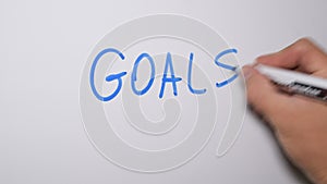 Writing the word GOALS with marker on white board