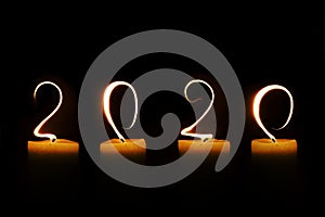 2020 written with candle flames on black background greeting card