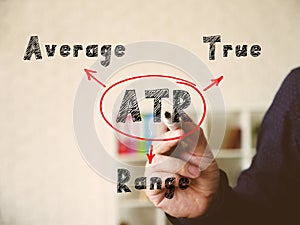 Written phrase ATR Average True Range . Hand holding a marker pen to write on officce background