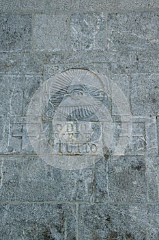 Written on the stone wall `Dio vede tutto`/`God sees everything` and masonic symbol above