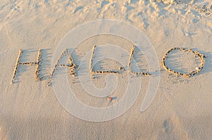 Written words Hallo on sand of beach