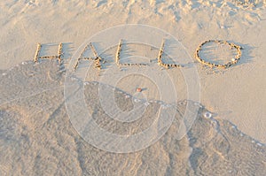 Written words Hallo on sand of beach