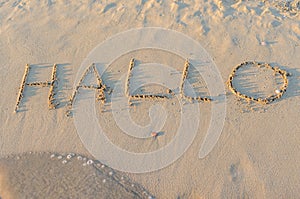 Written words Hallo on sand of beach