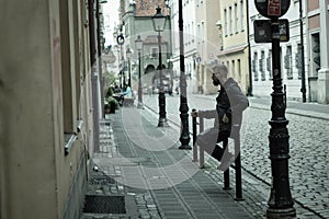 Wroclaw, Poland - May 10, 2019: A man sitting at an entrance of a house smoking in the polish old town of city center