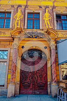 Wroclaw, Poland - 2012: Yellow stucco arc with beautifully decorated red wooden door with curve decor