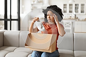 Wrong Parcel. Anxious black woman taking shoes out of box at home