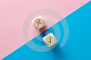 Wrong and right symbols on wooden cubes on pink and blue background