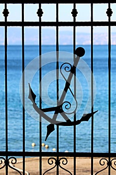 Wrought iron fence with decorative elements and silhouette of old antique vintage handmade anchor with decorations