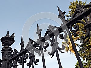 Wrought iron fence detail under blue sky. Bottom view of Vintage Antique Cast Iron Wrought Fence Finial Topper Fleur De Lis