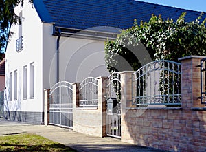 Wrought iron fence and green ivy. white house exterior with sloped clay roof