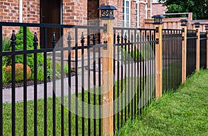 Wrought Iron Fence. Metal black fence around house with green lawn. Street photo