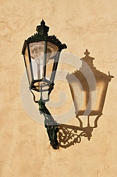 Wrought-iron lantern with its shadow on the yellow wall, Prague,