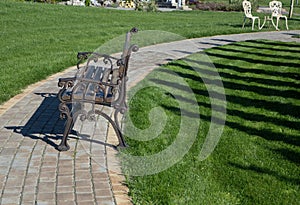 Wrought-iron park bench on a bright sunny summer day