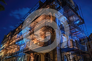 wrought-iron scaffolding with bright lights illuminating the exterior of a grand hotel