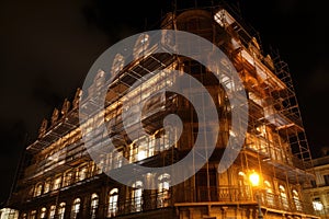 wrought-iron scaffolding with bright lights illuminating the exterior of a grand hotel