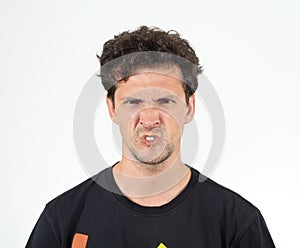 Young man grimacing against white wall