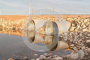 Wtwo steel culverts reflecting in water