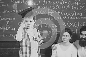 Wunderkind concept. Smart child, wunderkind in graduate cap pointing at his head. Boy presenting his knowledge to mom