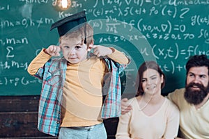 Wunderkind concept. Smart child, wunderkind in graduate cap pointing at his head. Parents listening their son