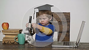 Wunderkind concept. Smart small boy, scientist child works with microscope, laptop. Concentrated kid with microscope