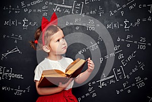 Wunderkind little girl schoolgirl with a book from the blackboar