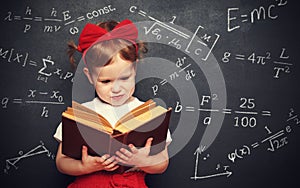 Wunderkind little girl schoolgirl with a book from the blackboar