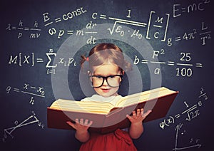 wunderkind little girl schoolgirl with a book from the blackboard with physical formulas