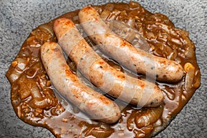 Wurst sausage in onion sauces serving on stone pan. Traditional German food