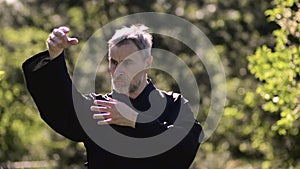 Wushu coach do exercise tai chi in the forest. Smooth hand movements