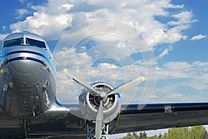 WWII Warbird headon with engine and wing in blue sky with clouds